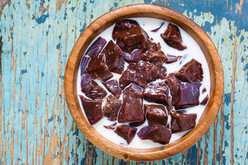 Slices of raw beef liver soaked in milk in a wooden bowl on the table. Top view