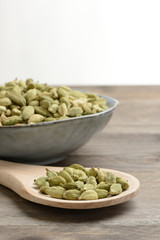 Cardamomo en un bol de cerámica en la mesa y una cuchara de madera