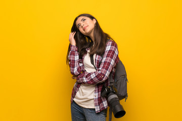Photographer teenager girl over yellow wall thinking an idea while scratching head
