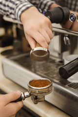 Vertical cropped shot of a barista preparing coffee using tamper for presing ground coffee into portafilter professionalism cafe working morning breakfast small business occupation job brewing concept