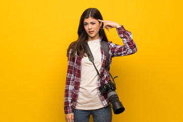 Photographer teenager girl over yellow wall making the gesture of madness putting finger on the head