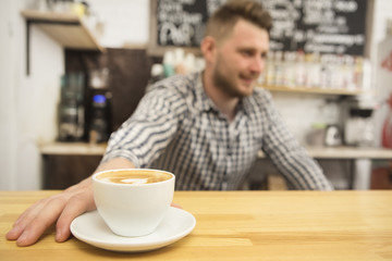 Selective focus on a cup of fresh coffee barista working at his coffee shop on the background copyspace profession occupation job entrepreneur owner startup small business businessman casual hipster