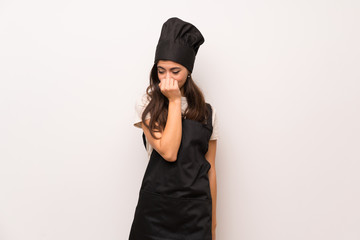 Teenager chef  over white wall having doubts