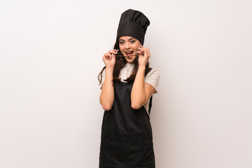 Teenager chef  over white wall with glasses and surprised