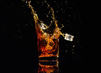 Isolated shot of whiskey with splash on black background