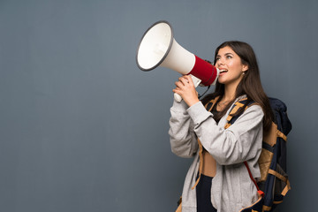 Teenager traveler girl over wall shouting through a megaphone