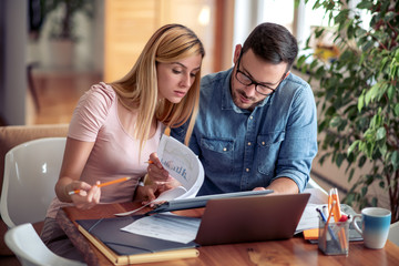 Couple at home paying bills with laptop