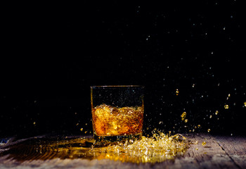 Isolated shot of whiskey with splash on wooden background