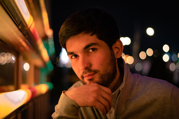 portrait of a young man at night in a city. neon lights, bokeh background.