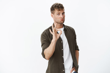 Nice not bad at all. Portrait of good-looking sportsman pulling lips up and showing okay gesture being impressed by good skills or product standing satisfied and affected over gray background