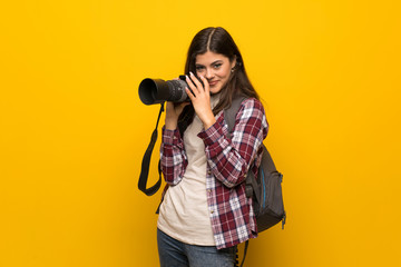 Obraz premium Photographer teenager girl over yellow wall
