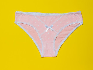 Cotton women's pink panties on a bright yellow background close-up. Beautiful lingerie. The view from the top.