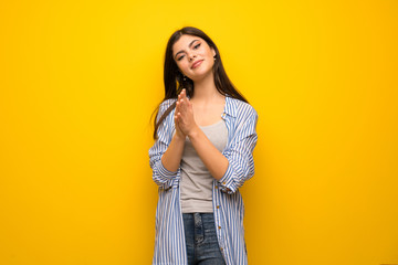 Teenager girl over yellow wall applauding after presentation in a conference