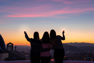 Silhouette of three girls looking to the sunset