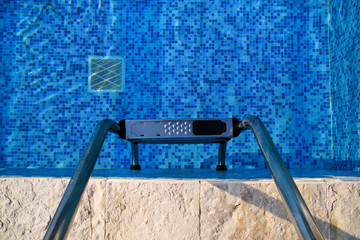 Handrail on pool. Swimming pool with stair at tropical resort. Pool handrails view. Water swimming pool with sunny reflection. Steel handrail, swimming, summer, travel. Entry to pool with handrail.