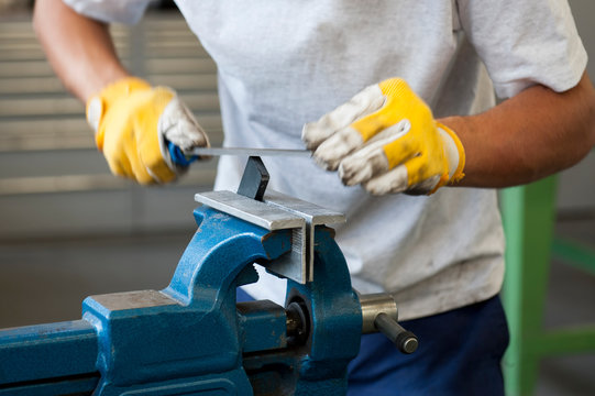 Handwerker feilt Metall, Werkst&uuml;ck im Schraubstock