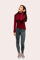 A full-length shot of a Teenager girl with turtleneck listening to something by putting hand on the ear over isolated background