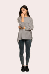 A full-length shot of a Teenager girl with striped shirt having doubts over isolated background