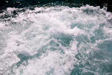 Turbulence made by foam of sea water from a high-speed yacht on surface of sea. Blue sea waves with...
