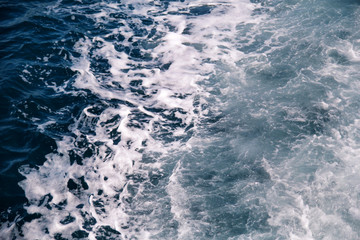 Fototapeta na wymiar Turbulence made by foam of sea water from a high-speed yacht on surface of sea. Blue sea waves with lot of sea foam. Surface of sea with waves, splash, foam and bubbles, blue background and wallpaper.