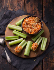 Delicious vegetable diet snack, celery stalks with carrot dip with nuts, garlic, spices and yoghurt dressing on on a wooden table
