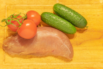 Raw duck breast with tomatoes and cucumbers. On the chopping Board.