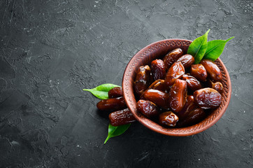 Dry date in a bowl on a black background. Dried fruit Top view. Free space for your text.