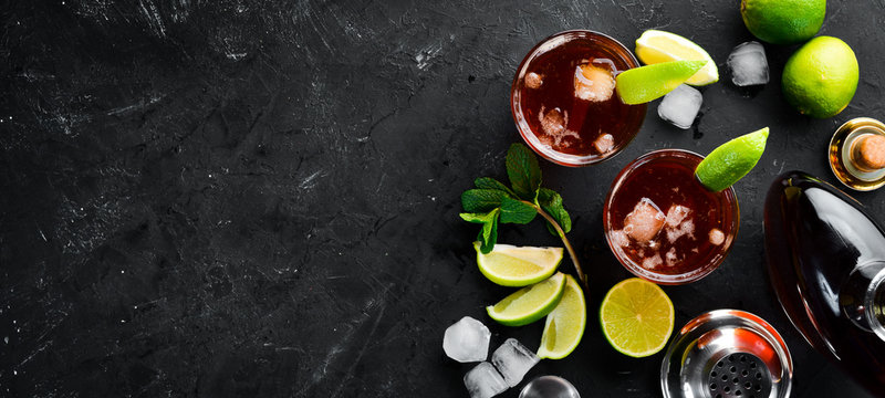 Alcoholic Beverage Rum, lime and mint on a black stone background. Top view. Free space for your text.