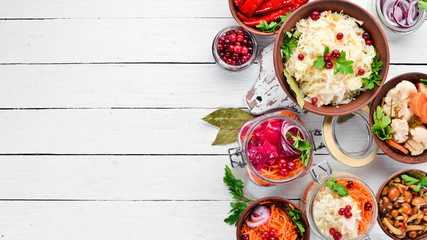 Pickled vegetables and mushrooms in a white kitchen table. Cabbage, mushrooms, cucumbers, cauliflower. Top view. Free space for your text.