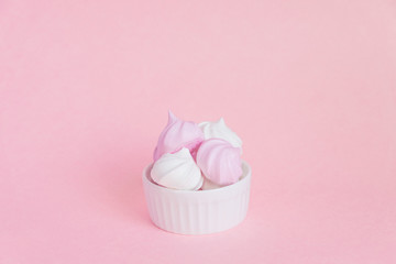  white and pink twisted meringues in porcelain bowl on pink background, greeting card, copy space