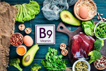 Foods that contain natural vitamin B9: Liver, avocado, broccoli, spinach, parsley, beans, nuts, on a blue background. Top view. - obrazy, fototapety, plakaty