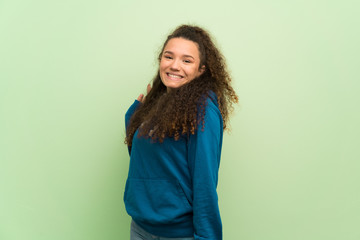 Teenager girl over green wall smiling