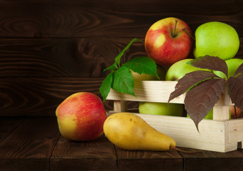 Apples in a wooden box on a wooden background. Red apples, green apples and pear. Delicious apple. Apples on table.