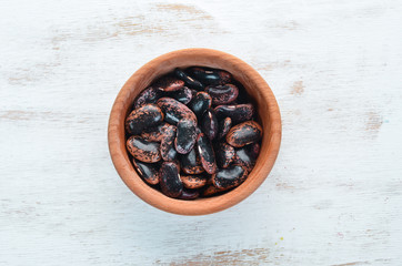 Raw beans in a bowl on a white wooden background.