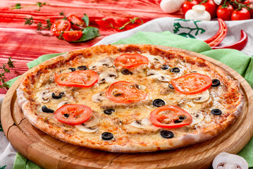 Fresh italian pizza with mushrooms, chiken, tomatoes, cheese, olive on wooden board, red rustic table. Copy space. Homemade with love. Fast delivery. Recipe and menu. Top view.