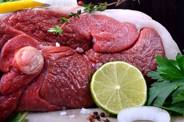 Raw mutton leg surrounded by herbs and spices