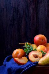 Red and yellow plums, pears and mint on a wooden table. Still life with copy space