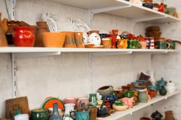 bright beautiful clay crafts standing on the shelves of the wall in the workshop