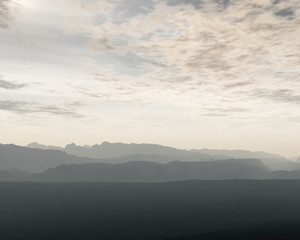 Mountain range in mist under cloudy sky.
