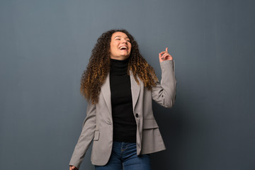 Teenager girl over blue wall smiling a lot