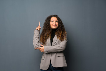 Teenager girl over blue wall pointing with the index finger a great idea