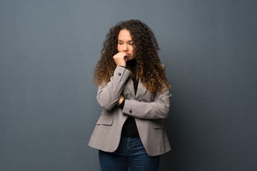 Teenager girl over blue wall having doubts