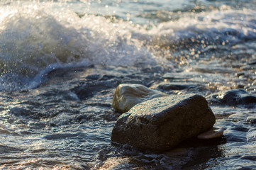 rocky sea shore with pebble beach, waves with foam