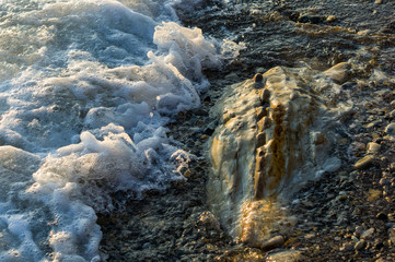 pebble stones on the sea beach, the rolling waves of the sea with foam