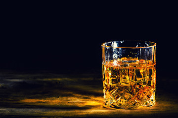 whiskey with ice cubes on wooden background