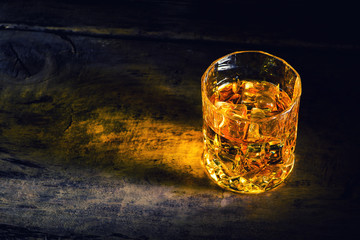 whiskey with ice cubes on wooden background
