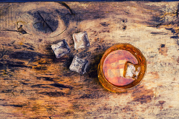 whiskey with ice cubes on wooden background