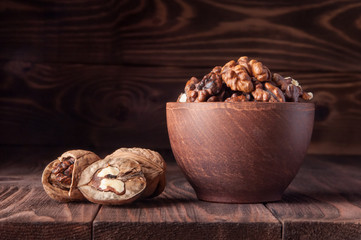 Walnuts on old rustic table. The kernels of a walnuts in a pot. Whole walnuts kernels. Beautiful walnuts and pieces of walnut.