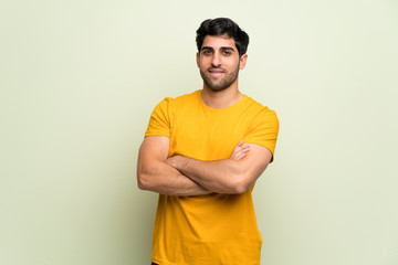 Young man over pink wall keeping the arms crossed in frontal position