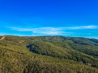 Fototapeta na wymiar Aerial view of drone, forest in mountain with wind turbines on ridge